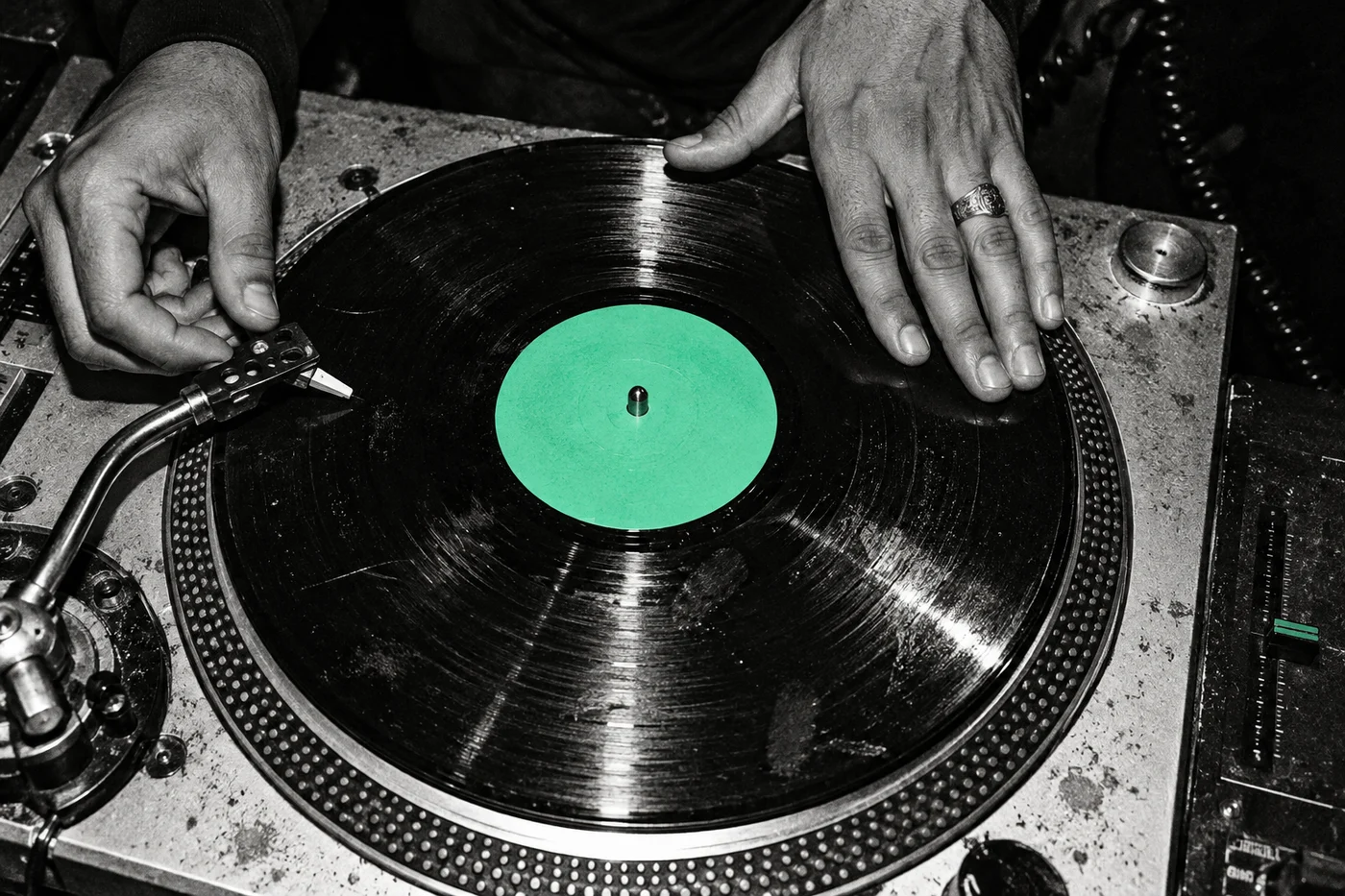 Close-up van handen op een zwarte vinylplaat met groen label